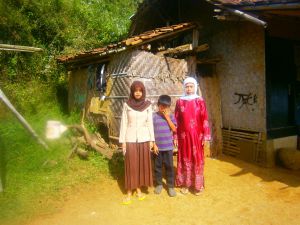 Ai, an orphan with her mother and brother in front of her house